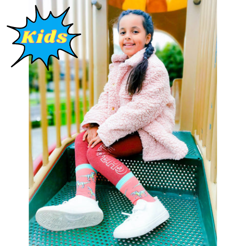 CLASSIC JURASSIC SOCKS - KIDS'. Pink background with t-rex pattern all over the socks. Teal toes and top of socks with lime green heal.