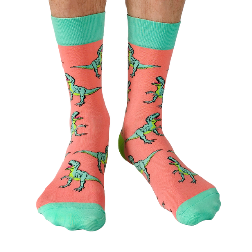 Pink socks with green dinosaur pattern worn by a person on a white background