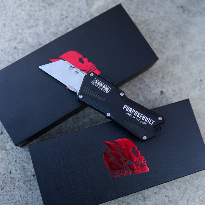 Knife with 'Pursue Built' branding on a black box with red logo on a concrete surface