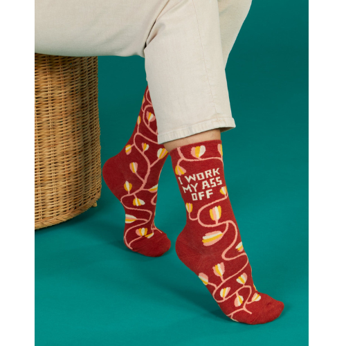 A pair of Blue Q socks with the phrase 'I Work My Ass Off' in bold letters, featuring a fun, colorful design for hardworking personalities.