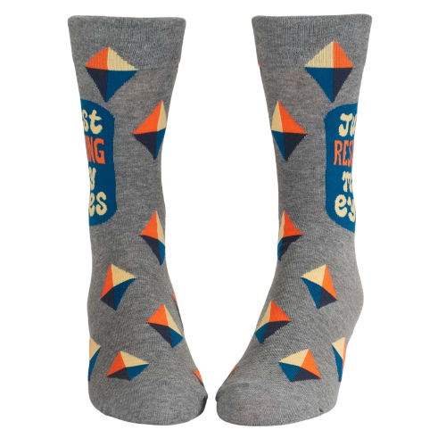 Blue Q men’s socks with the phrase ‘Just Resting My Eyes’ and a cartoon-style character lounging with eyes closed, in bold, playful design.