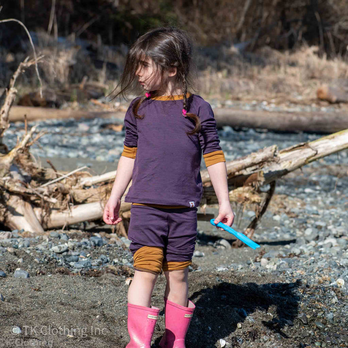 Child in TK Clothing Inc handmade base layer merino set and boots exploring rocky beach