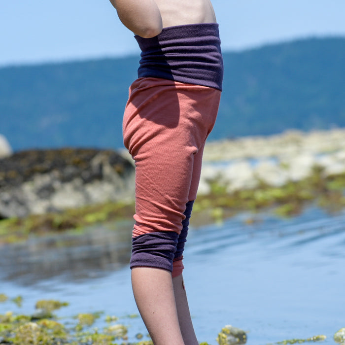 Child wearing handmade pink and purple leggings by TK Clothing Inc on rocky beach