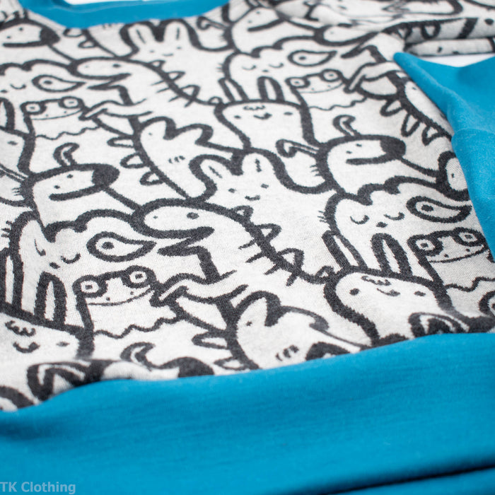 Close-up of TK Clothing Inc adventure print sweatshirt with playful animal doodles and blue trim