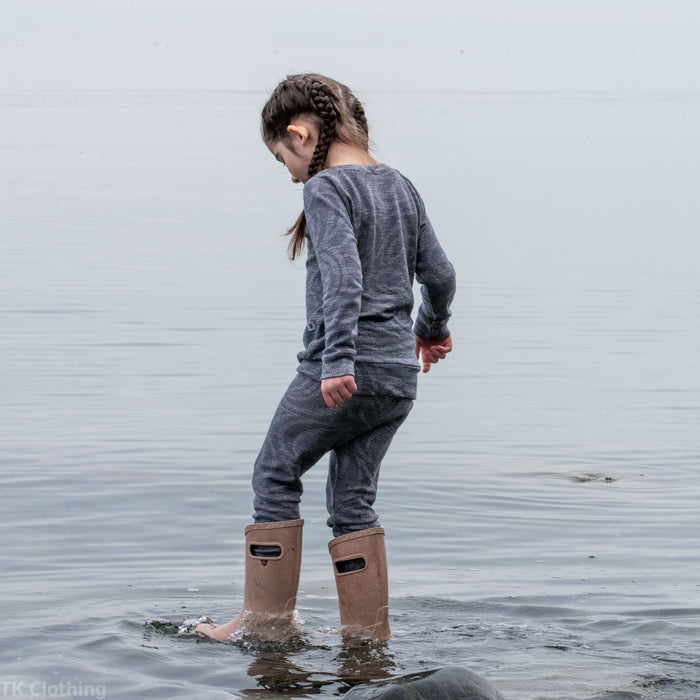 Child in grey adventure clothing and boots beachcombing in shallow water, TK Clothing Inc.