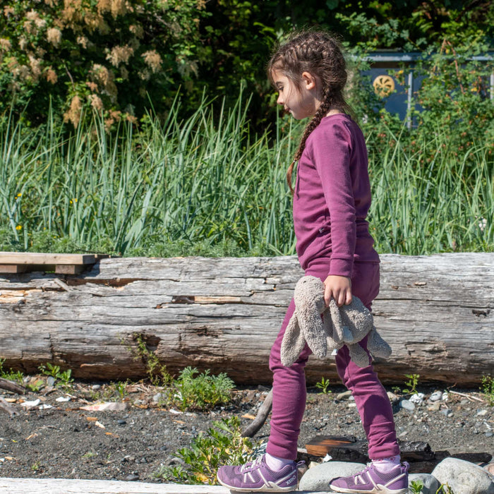 Child in purple adventure clothing walking outdoors, holding stuffed animal, TK Clothing Inc