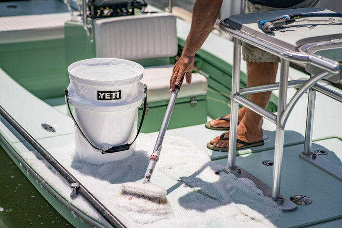 Worker scrubbing the white YETI Loadout bucket with soap, shown in use