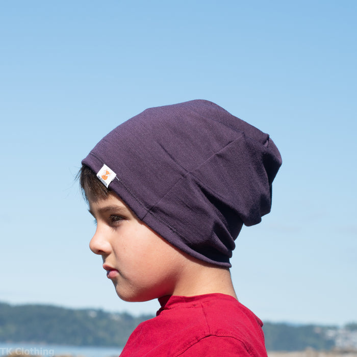 A child wearing a purple merino wool slouchie hat made by TK Clothing