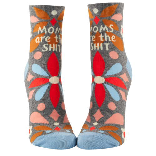 A pair of playful ankle socks by Blue Q, featuring the phrase "Moms Are The Shit" in bold, fun lettering. The design includes vibrant colors, whimsical patterns, and charming details, perfect for celebrating moms with a sense of humor and style.