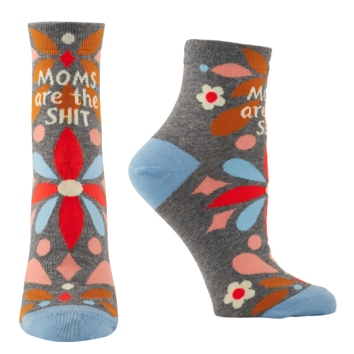 A pair of playful ankle socks by Blue Q, featuring the phrase "Moms Are The Shit" in bold, fun lettering. The design includes vibrant colors, whimsical patterns, and charming details, perfect for celebrating moms with a sense of humor and style.