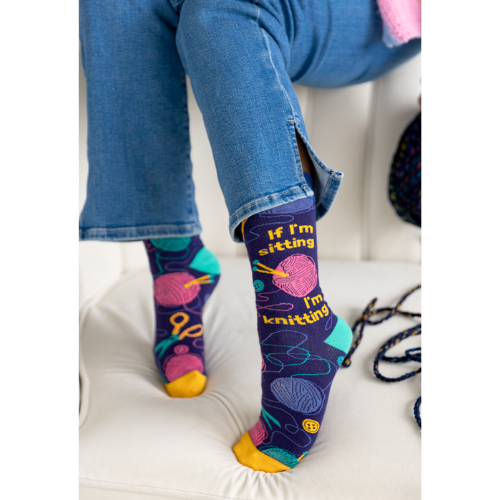 Women's crew socks with colorful knitting-themed designs, featuring the text 'If I’m sitting, I’m knitting.