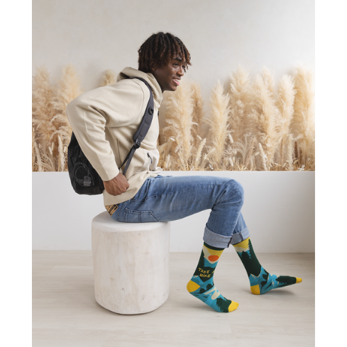 Pair of green, teal, and yellow men's crew socks with a mountain and sun design, featuring the phrase 'Take A Hike' on the side.