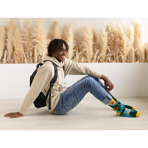 Pair of green, teal, and yellow men's crew socks with a mountain and sun design, featuring the phrase 'Take A Hike' on the side.