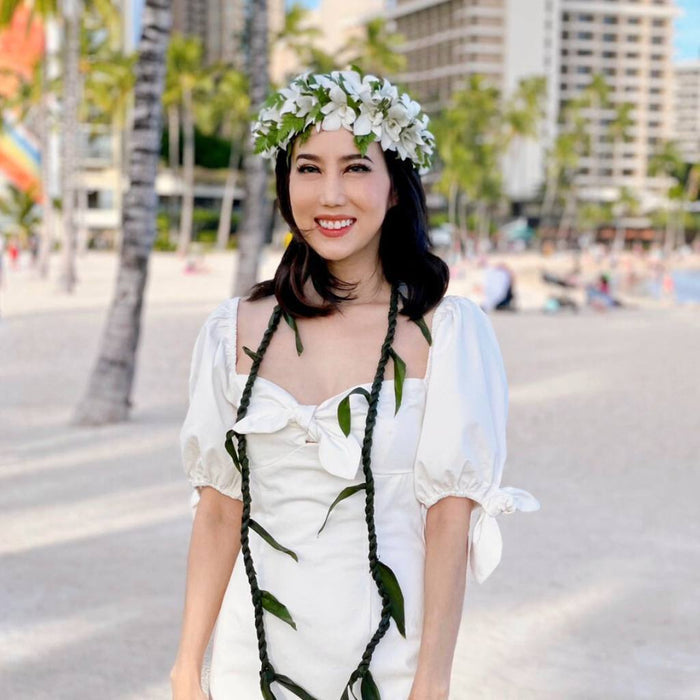 Woman in a white dress with Ti leaf lei & wearing white orchid flower crown ( haku )